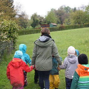BUND Kindergruppen-Betreuerin Hand in Hand mit Kindergartenkindern. 